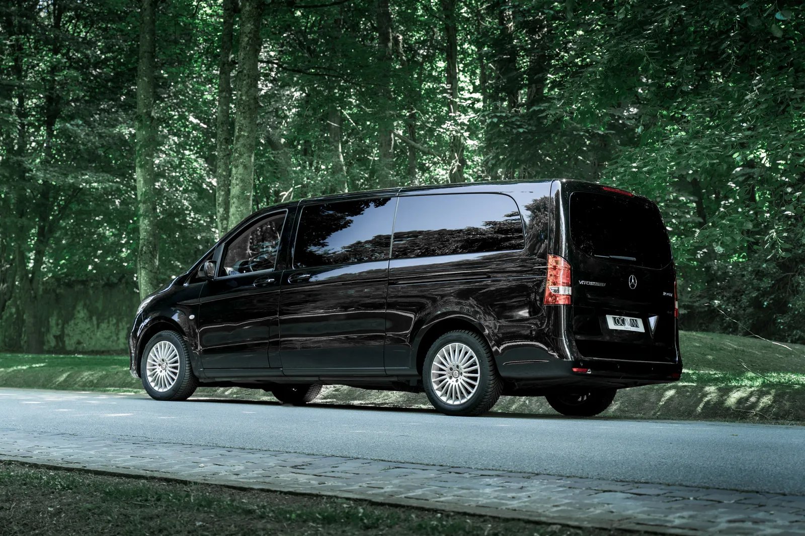 Minibus Mercedes Vito Tourer Locavan, vu de l'arrière, sur une route en forêt